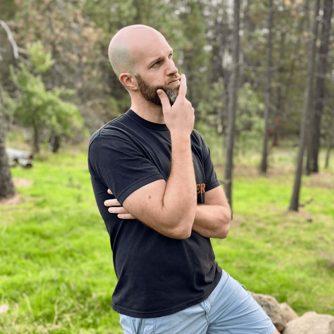 Thoughtful man outdoors in a black t-shirt contemplating choices in coffee.